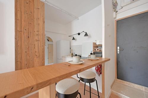- une cuisine avec un comptoir en bois et des tabourets dans l'établissement Le Petit Change - Clim - Hyper Centre, à Avignon