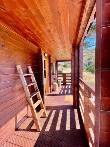 a porch of a wooden cabin with a ladder at Mountain Eco Shelter 3 in Corujeira de Dentro