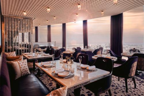 a restaurant with tables and chairs and a view of the city at Vacay Lettings - High floor Burj Khalifa & Fountain view 3 bed in Dubai