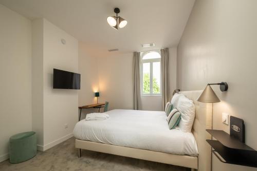 a white bedroom with a bed and a window at Maison Mimerel Colodge in Roubaix