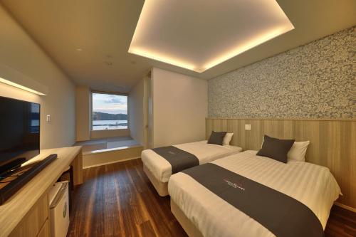 本部Marea Resort Motobu的一间有两张床和一台平板电视的酒店房间