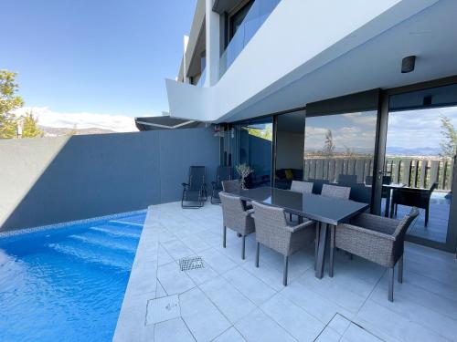 a dining room with a table and chairs next to a swimming pool at Casa Sonrisa-Ferienhaus mit eigenem Pool Urlaub für Familien und begeisterte Golfspieler in Caleta De Velez