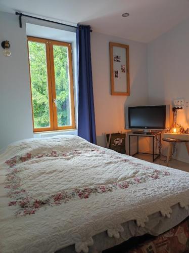 une chambre avec un grand lit et une fenêtre dans l'établissement Le pigeonnier d'Agnès, à Jenzat