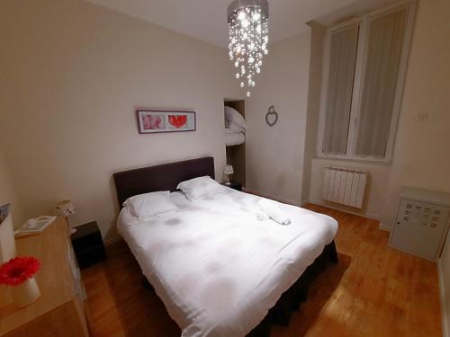 une chambre avec un lit avec des draps blancs et un lustre dans l'établissement Le Hoche - Apt 4 Personnes, 1 ch, Proche Gare, à Dijon