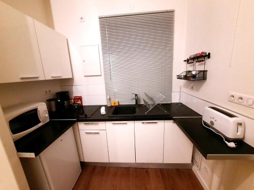 une cuisine avec des armoires blanches et un comptoir noir dans l'établissement Le Hoche - Apt 4 Personnes, 1 ch, Proche Gare, à Dijon