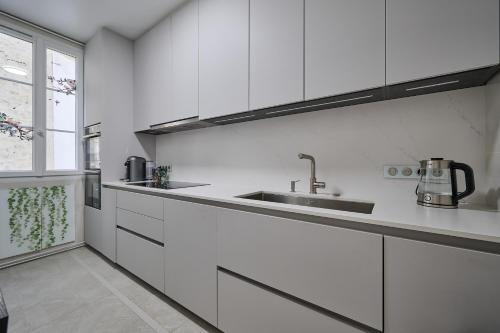 une cuisine blanche avec un évier et une fenêtre dans l'établissement Luxury Royal Suite, 118 square meters, notre dame, 3 bedrooms, à Paris