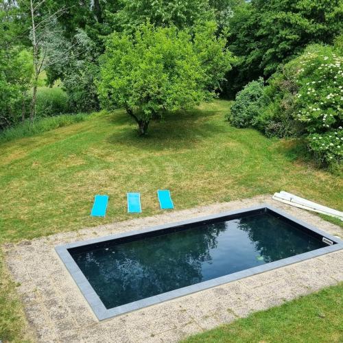 - une piscine avec deux chaises bleues dans la cour dans l'établissement Le Moulin de mon Père, 20 pers, Piscine, campagne., à Dompierre-sur-Nièvre