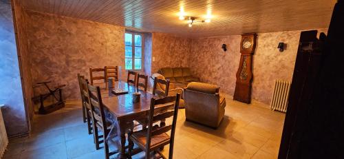 une salle à manger avec une table et une horloge grand-père dans l'établissement La Périgourdine, à Lacropte