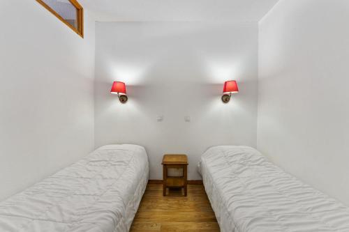 - 2 lits dans une chambre avec 2 lampes sur le mur dans l'établissement Résidence Les Hauts De Preclaux - Logement en plein coeur des Orres 1800 MAE-1071, aux Orres