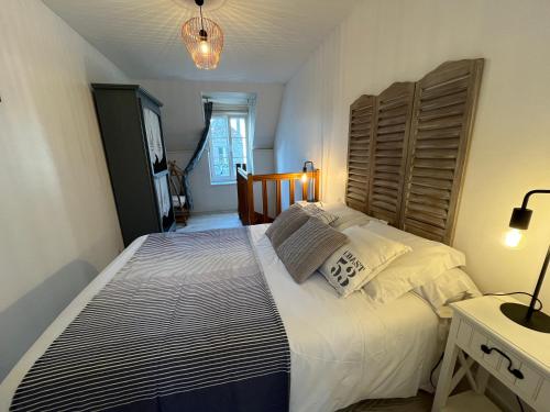 a bedroom with a large bed with a wooden headboard at Charmante maison de pêcheur 50 m de la plage et du Port in Barfleur