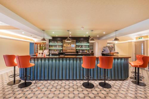 a bar in a restaurant with orange bar stools at The Riverside in Kendal
