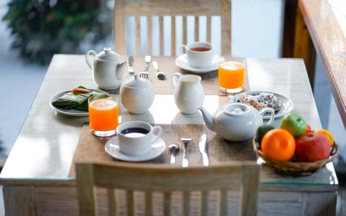BarangbarangSelayar Pearl Beach Cottage的一张桌子上摆着早餐，有茶、水果和橙汁。