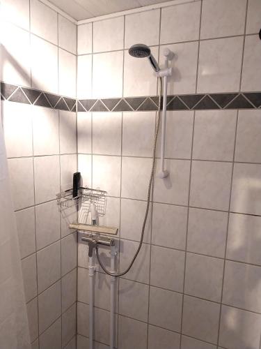 a shower in a white tiled bathroom with a shower head at Gæstebolig,Tørresøvej 87 in Otterup