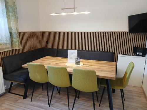 a wooden table with green chairs in a restaurant at Ennshäusl by Schladming-Appartements in Schladming