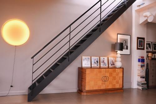 - un escalier dans un salon avec une commode en bois dans l'établissement Superbe loft avec terrasse et jacuzzi aux Lilas près de Paris, aux Lilas
