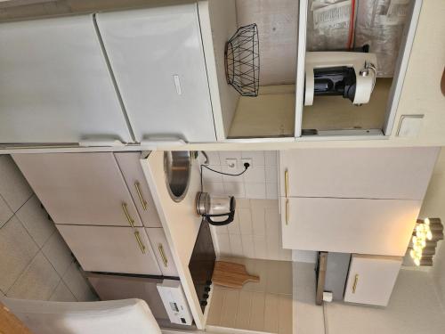 une petite cuisine avec des armoires blanches et un évier dans l'établissement Le Baïa - Fréjus Plage, à Fréjus