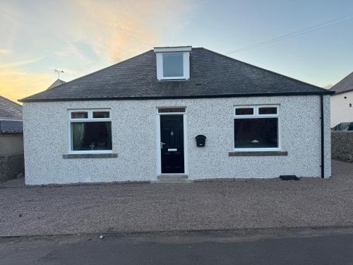a white brick house with a black door at Lorna Doune in Port Elphinstone