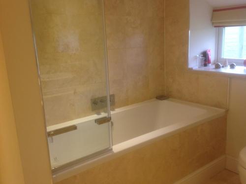 a bath tub with a glass shower in a bathroom at The Coach House in Ross on Wye