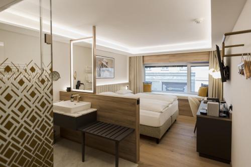 a bathroom with a bed and a sink in a room at Hotel Schwarzer Bär in Linz
