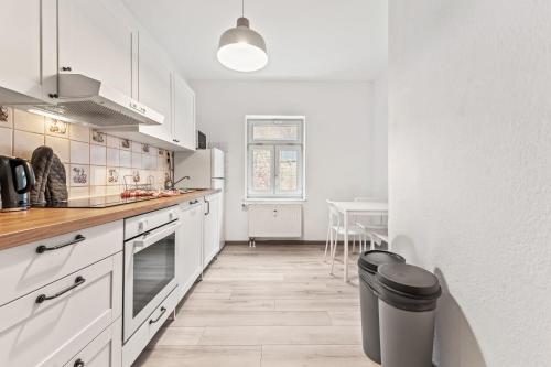 a kitchen with white cabinets and a trash can at Chic Apartment with Parking place in Apolda