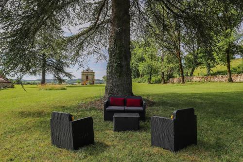 a couch sitting under a tree in a park at Chateau de Cambayrac, résidence exceptionnelle pour 12 personnes in Castanet