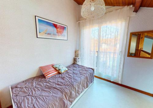 une chambre avec un lit et une fenêtre dans l'établissement LES ESTIVALES - Maison mitoyenne pour 4 personnes, à Capbreton