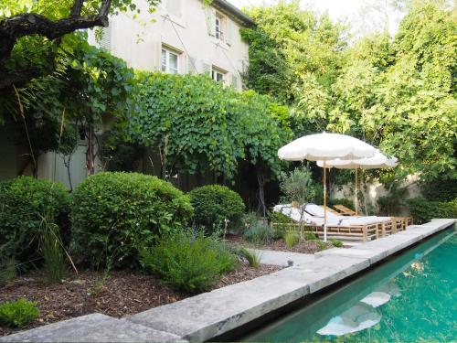 - un parasol et un banc à côté de la piscine dans l'établissement Le Mas Maillane, résidence du 18ème rénové, piscine et jardin privé, à Maillane
