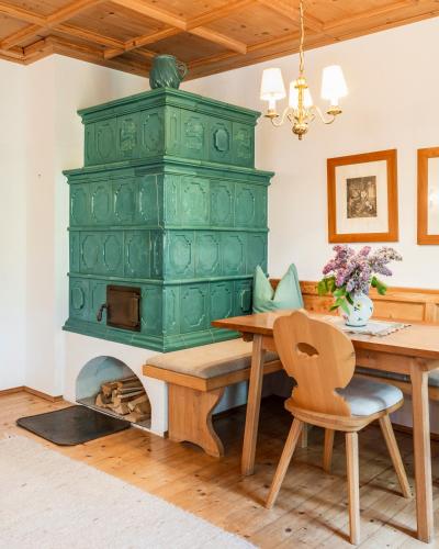 a green fireplace in a dining room with a wooden table at Romantikhotel Almtalhof in Grünau im Almtal