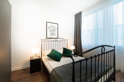 Un dormitorio con una cama con almohadas verdes y una ventana. en Reymonta 22 Apartamenty, en Opole