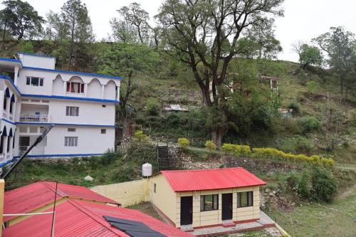 a building with a red roof next to a house at Cottage Paradise Point in Uttarkāshi