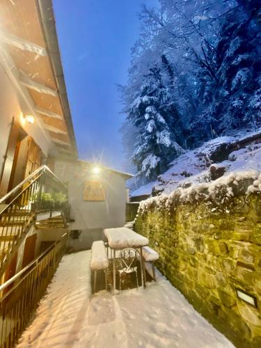 a table and chairs covered in snow next to a wall at PTHouse in Badia Prataglia