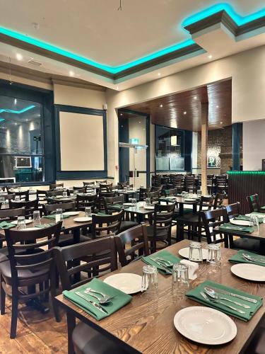 a dining room with tables and chairs and a screen at Green Ariana Hotel - near Wembley and central London in London