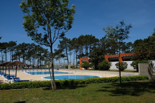 a swimming pool in a park with a tree at Parque de Campismo Orbitur Vagueira in Gafanha da Boa Hora
