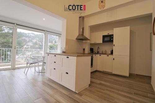 une grande cuisine avec des armoires blanches et une table dans l'établissement Anthénors, à Ensuès-la-Redonne