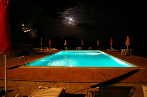 a swimming pool at night with a full moon at Casale delle Lucrezie by VacaVilla in Due Santi