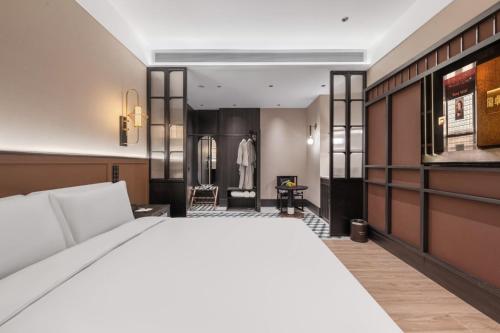a bedroom with a white bed and a dressing room at Yinzhuo Hotel - New Chinese decoration, free late-night supplies, free fruit, water and free snacks, close to the International Convention and Exhibition Center, Embassy, Sanlitun, Bird's Nest, close to Sanyuan Bridge of Metro Line 10 and Airport Line in Beijing