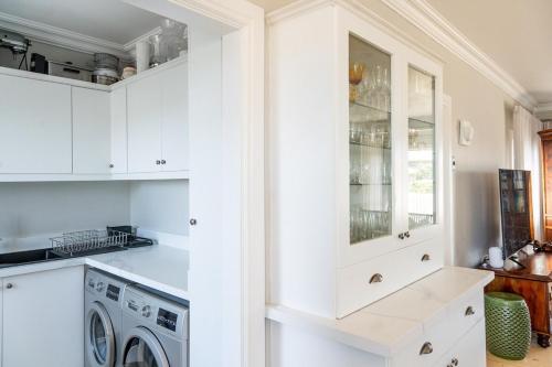a kitchen with white cabinets and a washer and dryer at SandDollar - Entire house in Cape St Francis