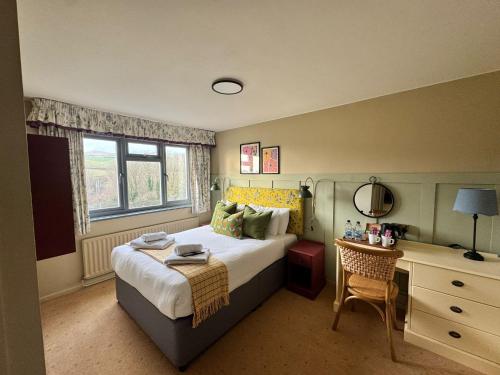 a bedroom with a bed and a desk with a chair at Eype's Mouth Country Hotel in Bridport