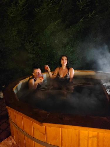 a man and a woman sitting in a hot tub at Chata pod lasem in Myślenice
