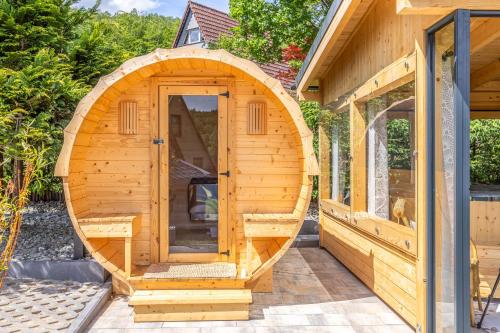 a wooden sauna with an arched door on a house at Kaszubska Kryjówka - Komfortowy 8 osobowy Domek w sercu Kaszub - Jacuzzi, Sauna, Rowerek Wodny, Jezioro, Las, Salon Gier! in Sulęczyno