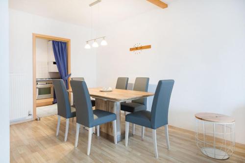 a dining room with a wooden table and blue chairs at Ferienhaus Nr 4, Kategorie Premium L, Feriendorf Hochbergle, Allgäu in Lechbruck