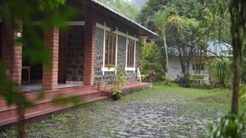 a brick house with a porch and a window at Dew Drops Farm Resorts in Munnar
