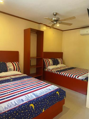 a bedroom with two beds and a ceiling fan at Siargao Sunset Bay Beach Villas in General Luna