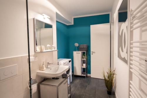 a bathroom with a white sink and a blue wall at ANER 4 Design Apartment Zoe in Dresden