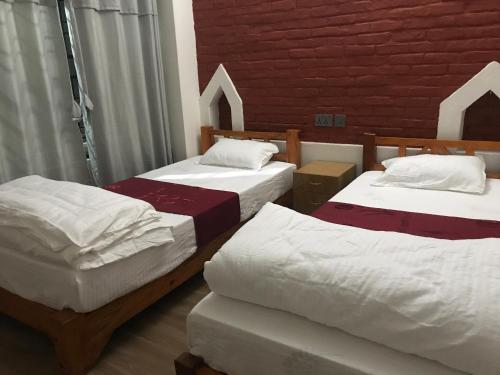 a bedroom with two beds and a red brick wall at Mount Fuji Homestay in Deorāli