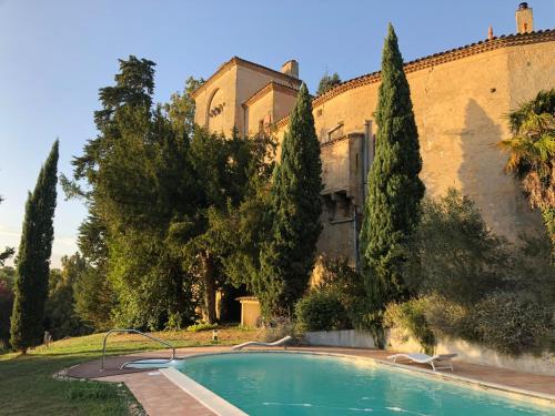 une piscine devant un immeuble avec des arbres dans l'établissement Château de Savignac, à Savignac