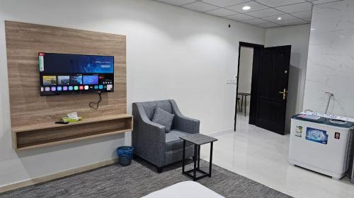 a room with a chair and a tv on a wall at الخالديه للشقق المخدومه in Al ‘Awālī