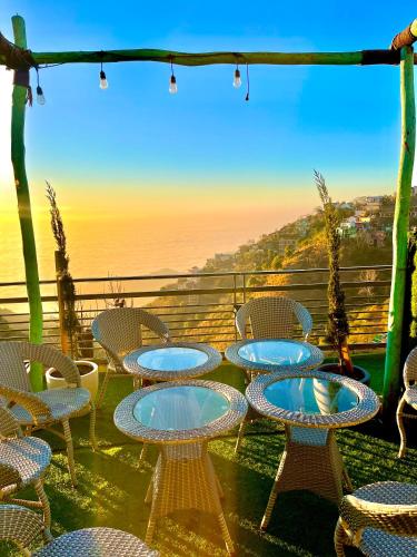 a patio with tables and chairs and the ocean at Vanshika homes Near mall road in Kasauli