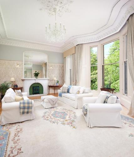 a large living room with white furniture and a chandelier at 7 Crown Gardens Glasgow in Glasgow