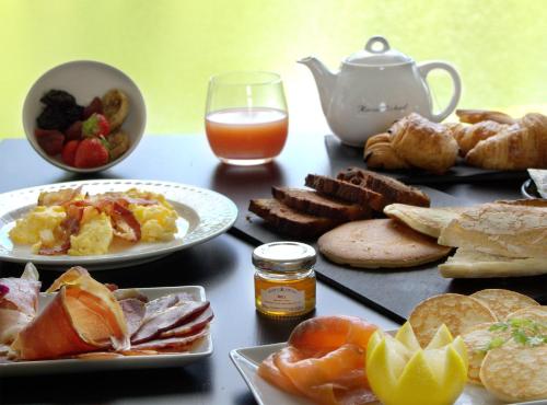una mesa con platos de comida y un vaso de jugo de naranja en Saint Malo Golf Resort, en Le Tronchet